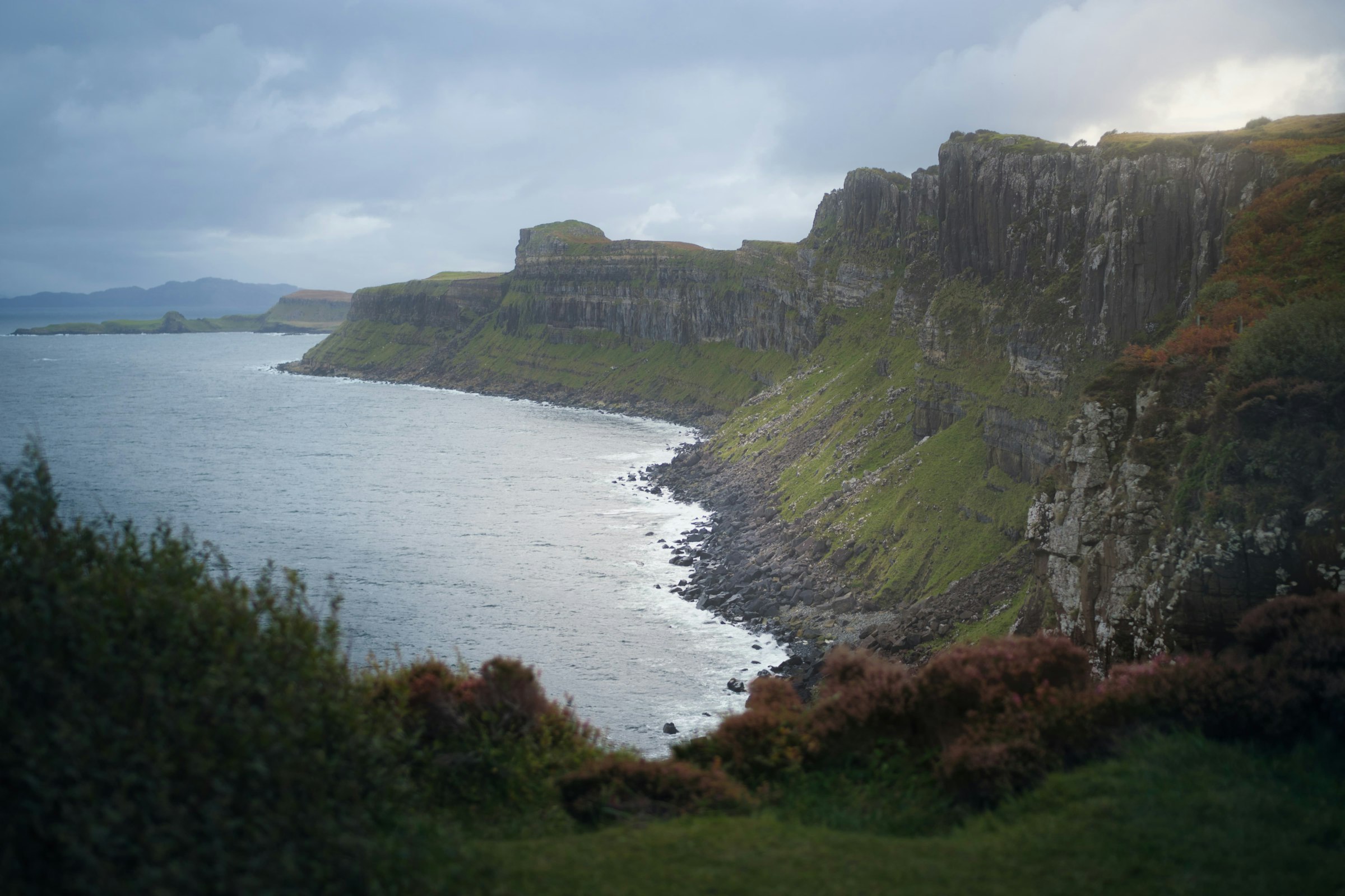 Tall sea cliffs and a green hillside above calm water in the Scottish islands