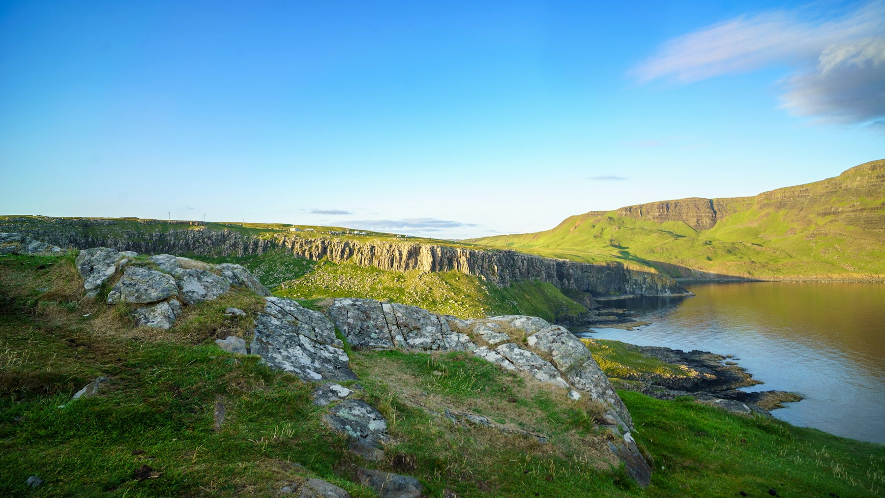 A quiet cove below green sea cliffs on the Scottish coast